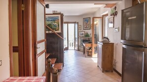 A kitchen with a refrigerator, wooden cabinets, and a dining area with a table and chairs. - S267 - Sirolo , portion of a single villa surrounded by the greenery of Conero (Sirolo)