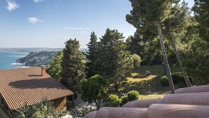 A coastal view with a tiled roof building, surrounded by trees and a clear sky. - S267 - Sirolo , portion of a single villa surrounded by the greenery of Conero (Sirolo)