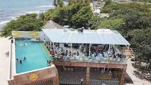 Zona de piscina con un área de estar techada con vistas al océano.