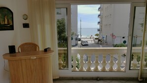Une pièce avec un comptoir d’accueil en bois, une vue sur la rue et un balcon doté d’une balustrade blanche.