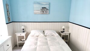 Une chambre à coucher comprenant un lit, deux tables de chevet, une commode et un tableau accroché au mur.