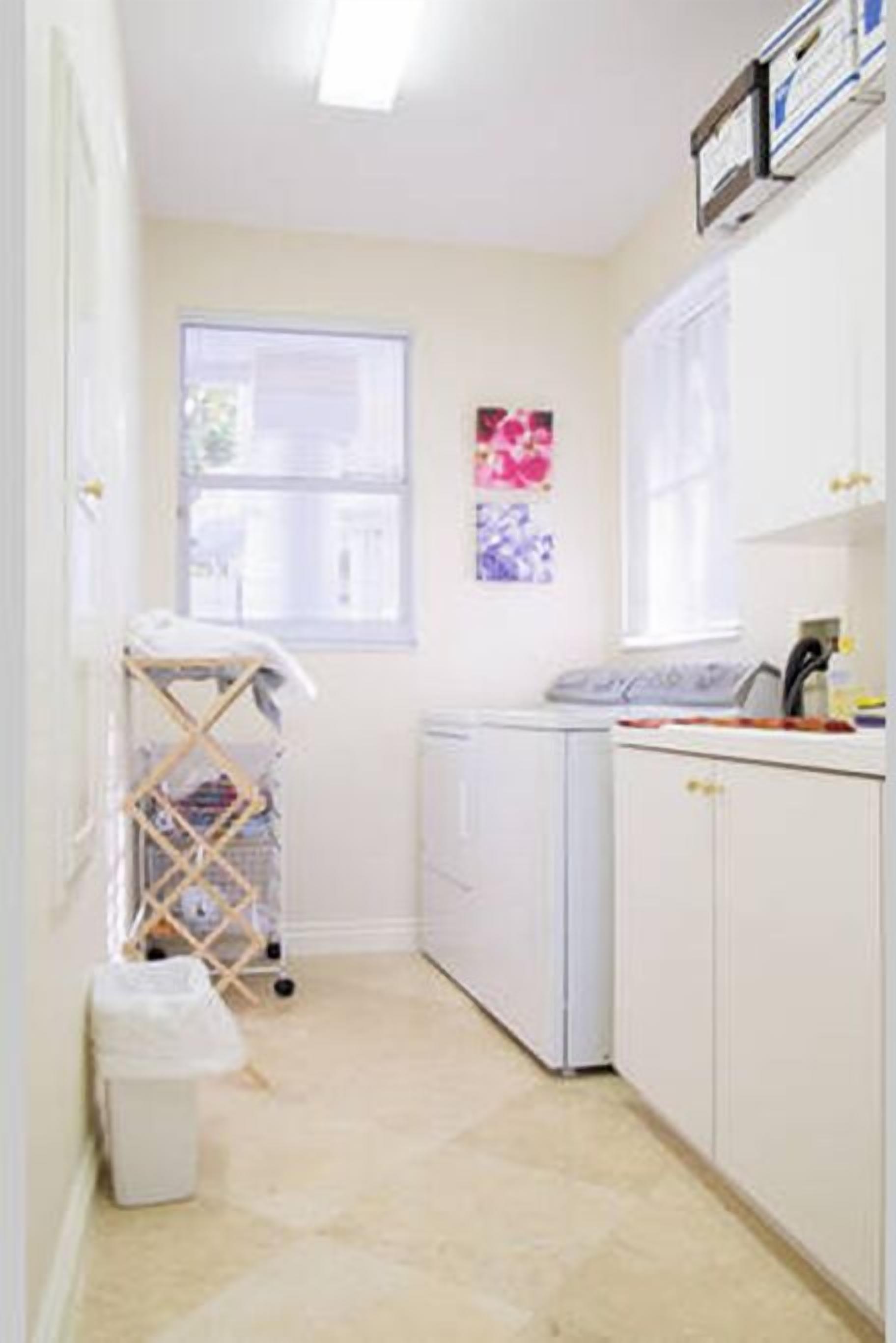 A laundry room with a washing machine, a drying rack, and a trash bin.