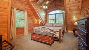 Ein Schlafzimmer einer Holzhütte mit Bett, Schminktisch und Deckenventilator.