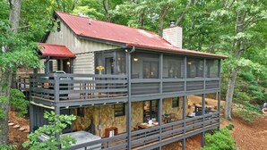 A two-story cabin with a red roof, large windows, and a balcony. - Mountain Crest Cottage Fabulous Fire Pit and 5 Minutes to Downtown Blue Ridge!  (Blue Ridge)