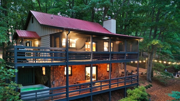 A two-story cabin with a red roof, multiple windows, and a balcony. - Mountain Crest Cottage Fabulous Fire Pit and 5 Minutes to Downtown Blue Ridge!  (Blue Ridge)