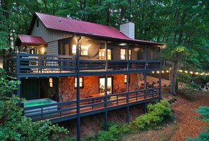 Une cabane à deux étages, avec un toit rouge, de nombreuses fenêtres et un balcon.