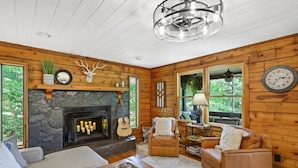 A cozy log cabin interior with a stone fireplace, leather sofas, and a wooden ceiling. - Mountain Crest Cottage Fabulous Fire Pit and 5 Minutes to Downtown Blue Ridge!  (Blue Ridge)