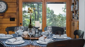 A dining table set with plates, glasses, and a centerpiece of flowers and candles.