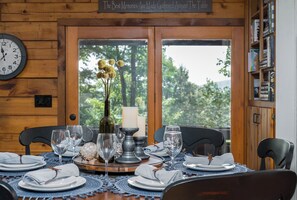 Une table à manger dressée avec des assiettes, des verres et un centre de table composé de fleurs et de bougies.