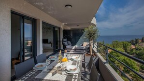 A balcony with a dining table set for two, overlooking a scenic view. - Playa Marina (Bastia)