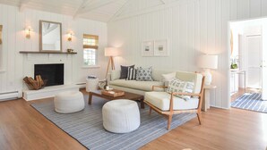 Ein Wohnzimmer mit Kamin, Sofa, Hocker und Couchtisch.