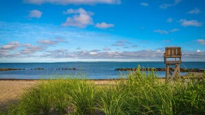 Ein Strand mit Rettungsschwimmer-Sitz, blauem Himmel und ruhiger See.