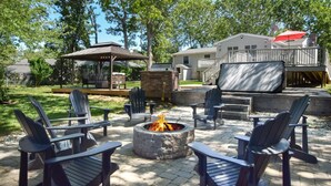 Un patio al aire libre con sillas Adirondack, un hogar para fogata y una zona de estar cubierta.