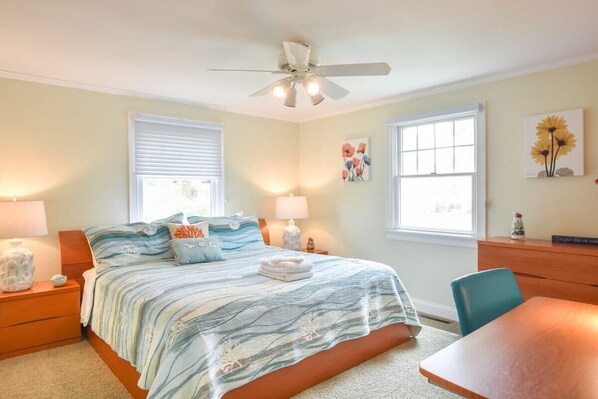 A bedroom with a bed, bedside tables, a ceiling fan, a window, and a desk. - Walkable to beaches. Hot Tub and Dog Friendly! (South Yarmouth)