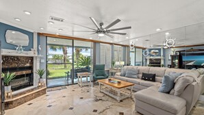 A spacious living room with a fireplace, a ceiling fan, and a large window offering a view of the outdoors. - Beautiful Mainsail Townhome Sleeps 8 .   3 bedrooms3 bathrooms Gated Community  (Miramar Beach)
