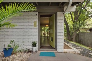 Welcome to a serene entrance, flanked by lush greenery and a beautiful garden.