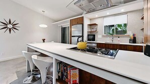 Une cuisine moderne dotée d’un îlot central, d’appareils électroménagers en acier inoxydable et d’un élément décoratif mural.