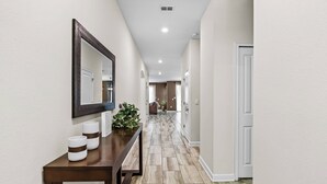 A hallway with a wooden console table, a mirror, and a potted plant.