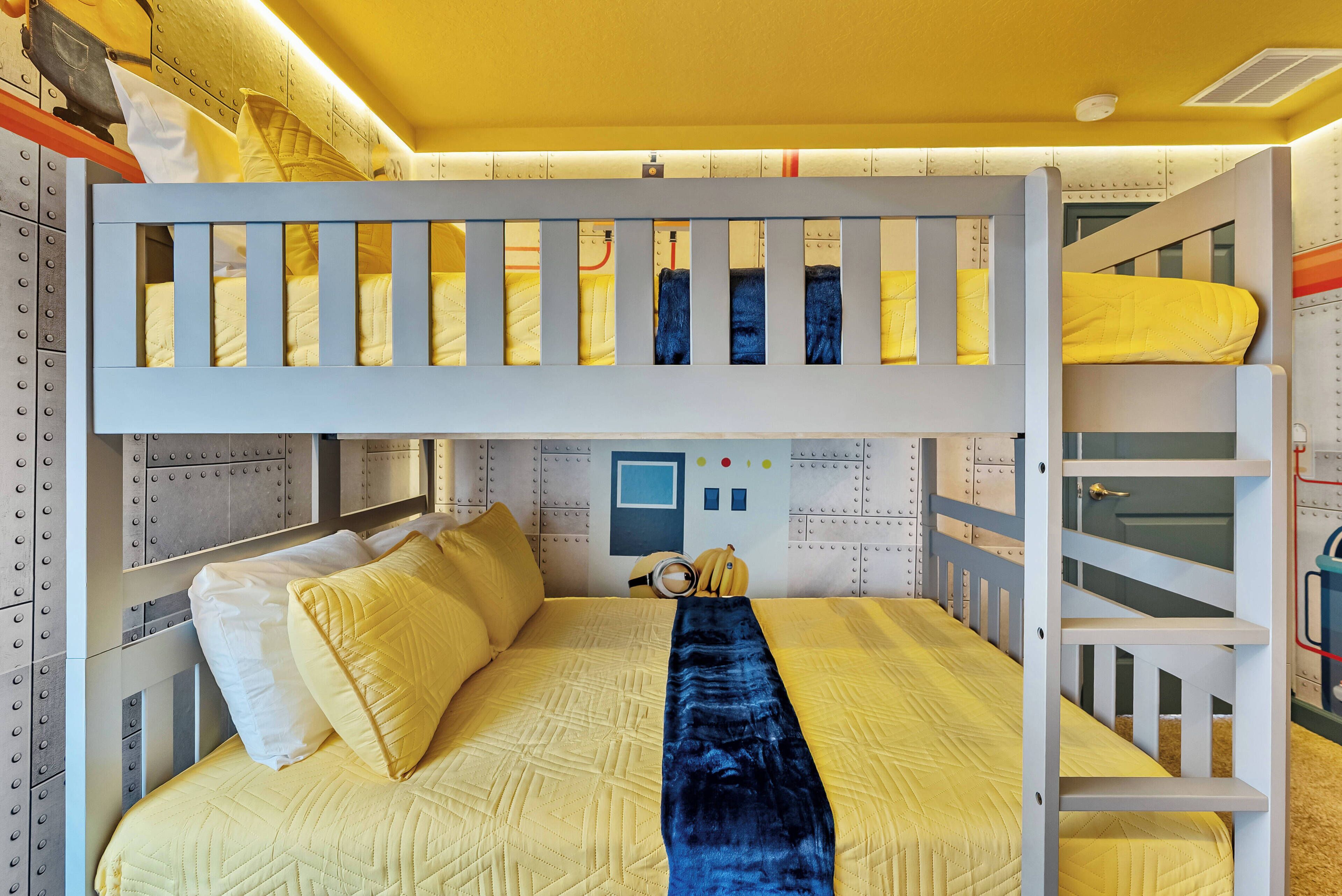 Un lit superposé avec un matelas jaune matelassé, des oreillers blancs et une couverture bleue.