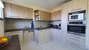 A modern kitchen with wooden cabinets, a dishwasher, a microwave, and a coffee maker. - Port FREJUS 3 air-conditioned rooms 80m2 4 people near beaches and nature base (Fréjus)