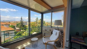 A balcony with a view of buildings and trees, a chair, a small table, and a lamp. - Port FREJUS 3 air-conditioned rooms 80m2 4 people near beaches and nature base (Fréjus)