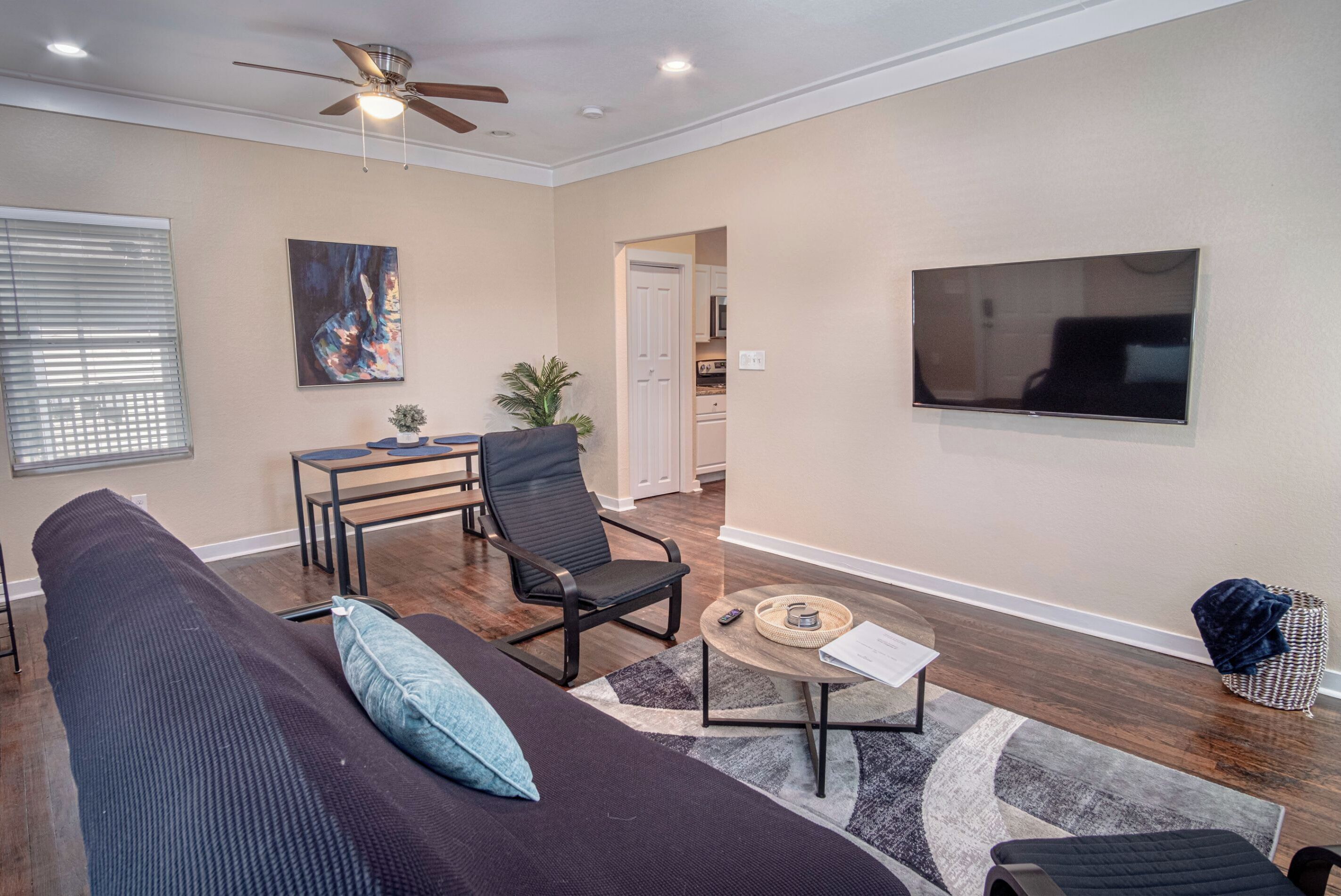 A living room with a sofa, a coffee table, a TV, and a ceiling fan.