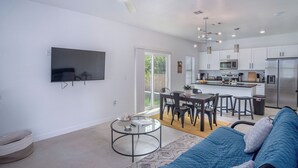 A modern living room with a TV, a round coffee table, and a blue sofa. - Experience Modern Luxury! 3br/2.5ba Home Near DT (San Antonio)
