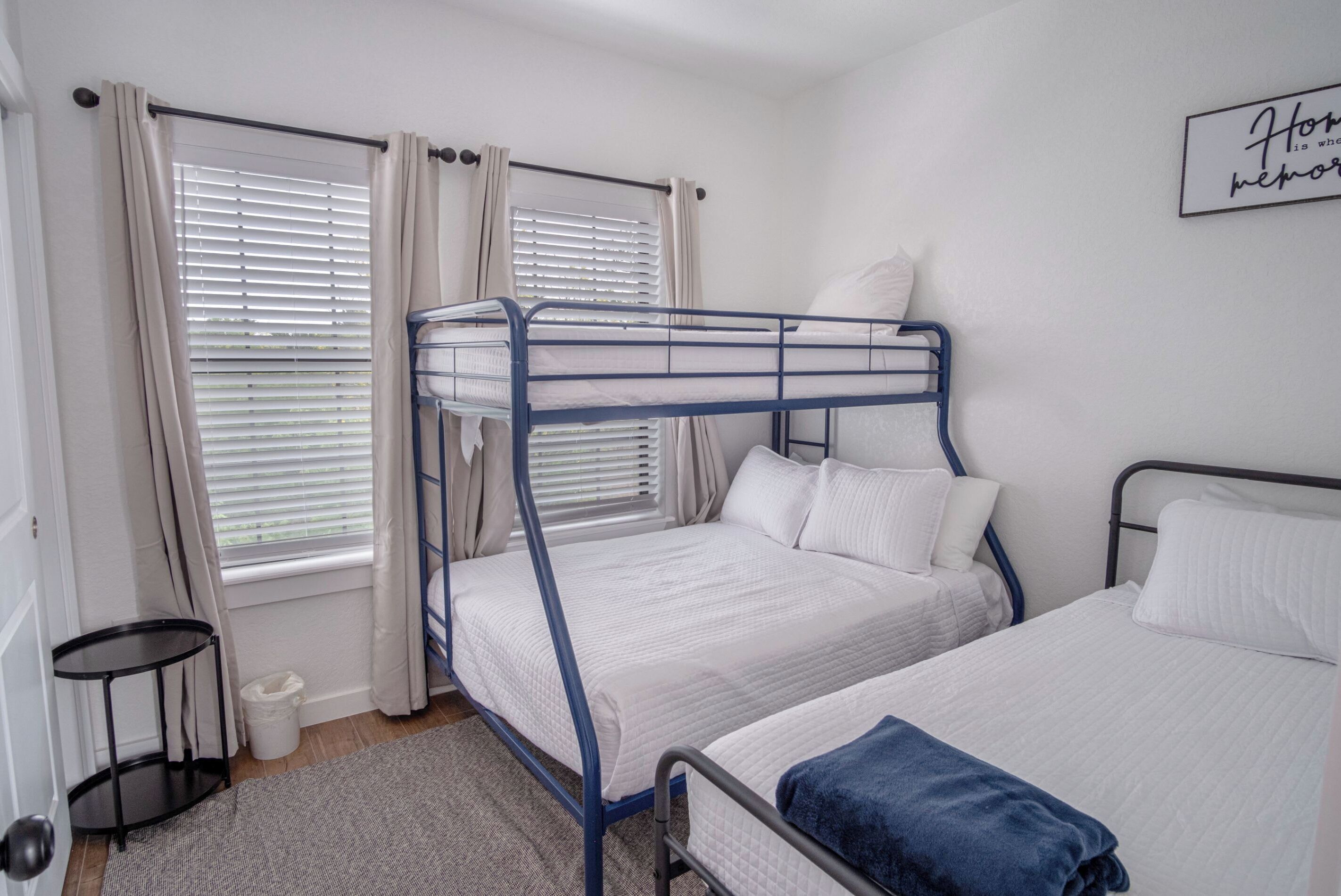 Een slaapkamer met twee stapelbedden, een klein tafeltje en een raam met gordijnen.