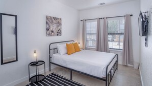 A bedroom with a bed, a ceiling fan, a wall-mounted TV, and a window with curtains. - Experience Modern Luxury! 3br/2.5ba Home Near DT (San Antonio)