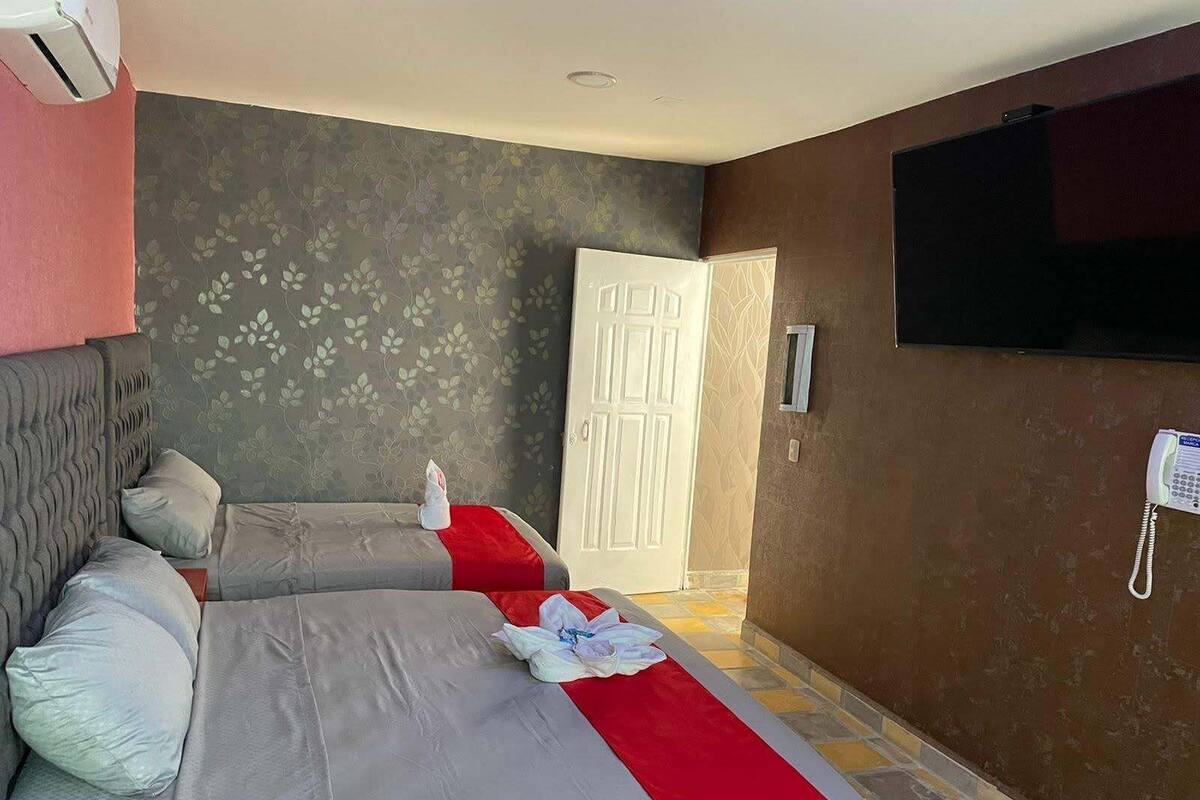 A hotel room with two beds, a TV, a telephone, and a door.