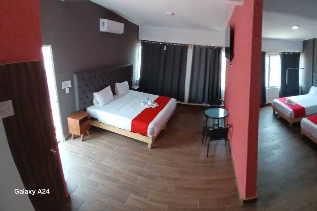 A hotel room with two beds, a small table, and a chair.
