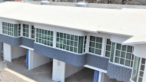 Um edifício com telhado plano, várias janelas e vista para o mar.