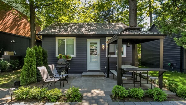 A patio area with a covered seating area, a small table, and chairs. - beachfront (Wasaga Beach)