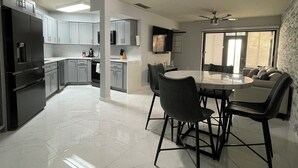 A modern kitchen with a dining area, featuring a large island, dark cabinets, and a ceiling fan. - Modern Resort-Style Stay (Orlando)