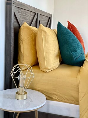 Relax in a stylish seating area with a sofa, side table, and geometric-patterned headboard.