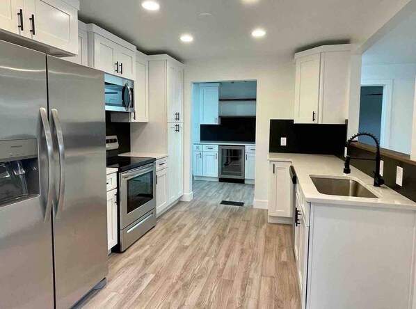Kitchen features sleek appliances, light-colored cabinetry, and a large sink.
