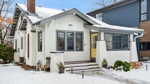 Ein eingeschossiges Haus mit weißer Fassade, einer gelben Haustür und der Hausnummer 4112.