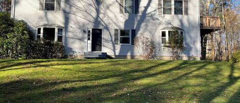 A two-story house with a front porch, a deck, and a yard.