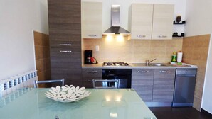 Une cuisine moderne avec une table à manger en verre, des appareils électroménagers en acier inoxydable et des meubles de couleur claire.