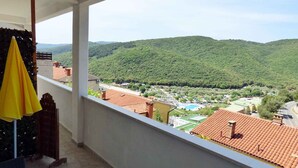 Un balcon avec vue sur une vallée verdoyante et une piscine.