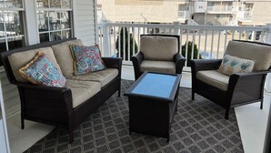 Un balcone con mobili in vimini, tra cui un divano e due poltrone, più un tavolino.