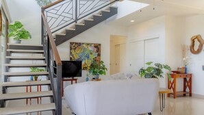 A modern living room with a staircase, a sofa, and a flat-screen TV.