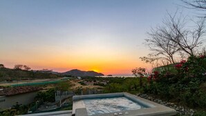 A hot tub with a view of the sunset and mountains.