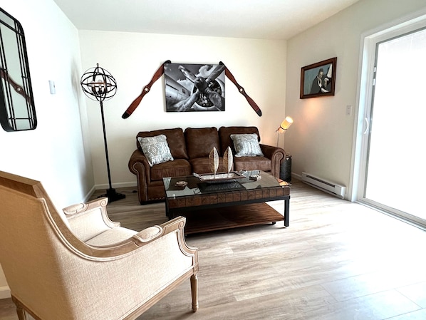 Ein Wohnzimmer mit einem braunen Ledersofa, einem Glastisch und einem Holzstuhl.