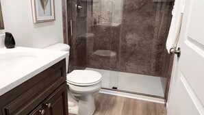A bathroom with a shower, toilet, and vanity. - *Aviate to the Lake* Downtown Lake Geneva (LAKE GENEVA)