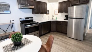 A modern kitchen with dark wooden cabinets, stainless steel appliances, and a white countertop. - *Aviate to the Lake* Downtown Lake Geneva (LAKE GENEVA)