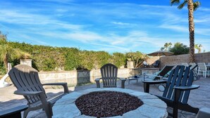 An outdoor seating area with Adirondack chairs and a stone fire pit.