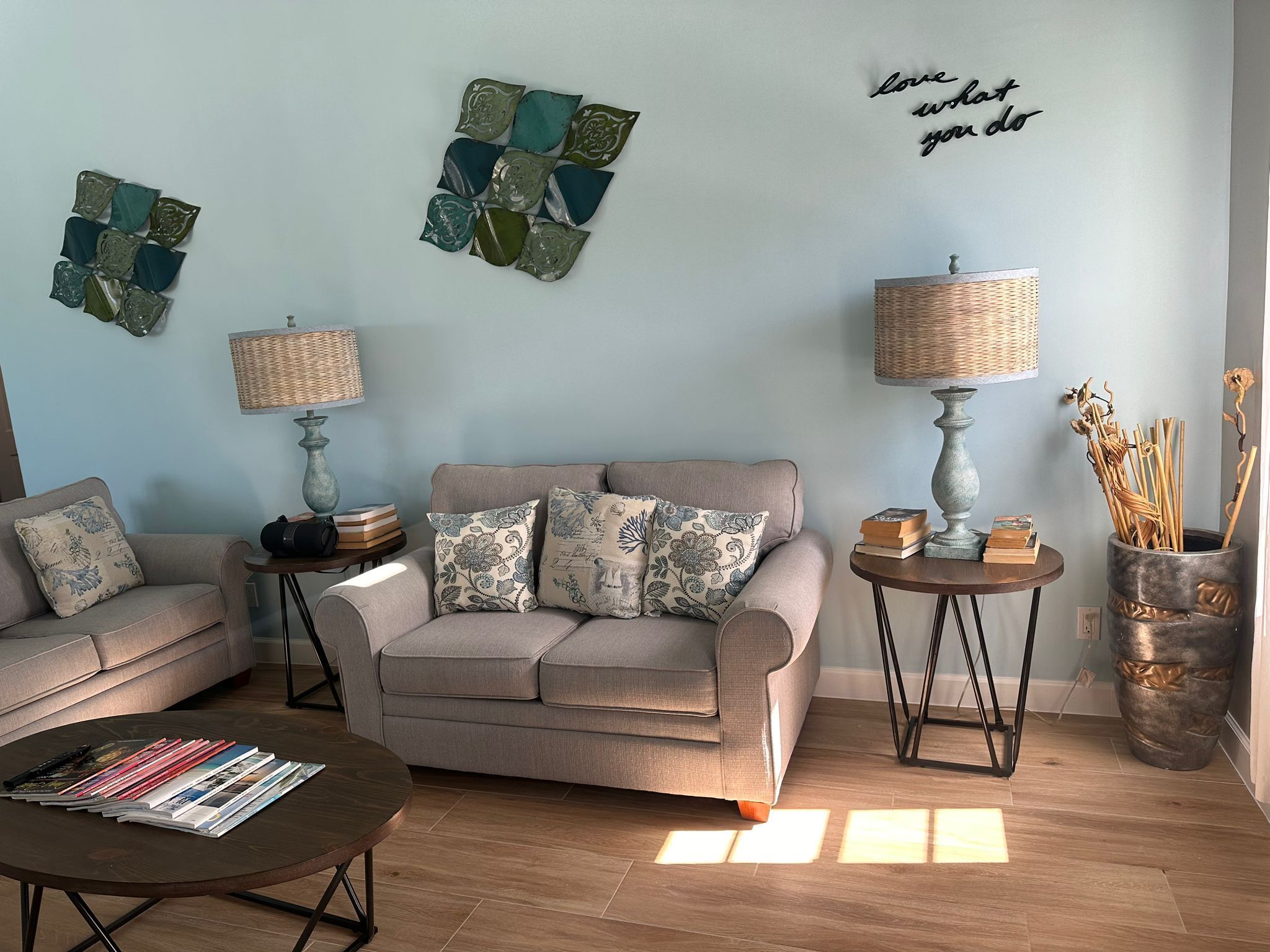 A living room with a sofa, two side tables, a coffee table, and decorative wall art.