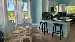 A modern kitchen with a central island, white cabinetry, and a dining area with a round table and chairs. - Beautiful villa West with pool- 5 minutes to Gracebay beach (Providenciales)