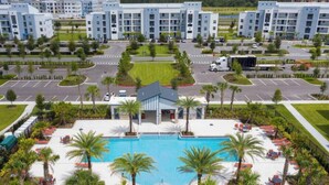 Un resort con piscina central, palmeras y estacionamiento.